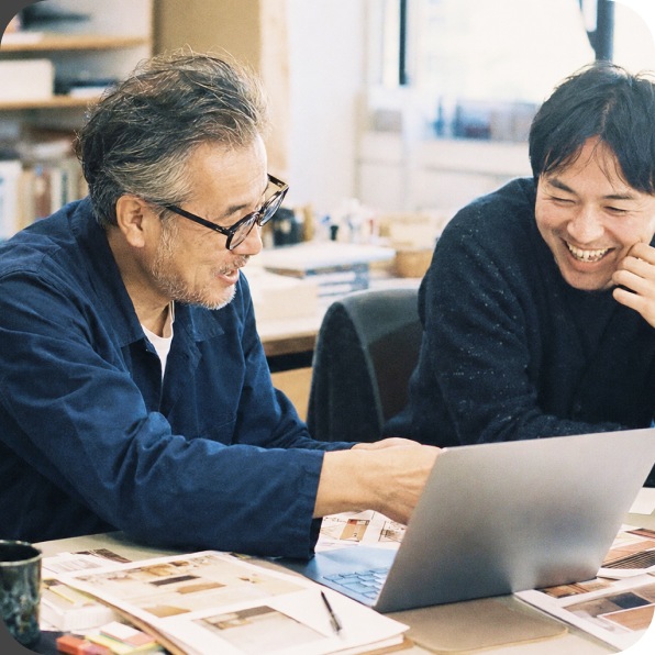 事務所でノートPCを開いて話し合う二人