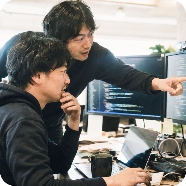 モニターを見ながら相談する開発者ふたり